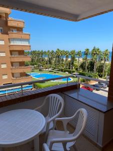ein Balkon mit Tisch und Stühlen und ein Swimmingpool in der Unterkunft VISTA MAR I - Magic World in El Borseral