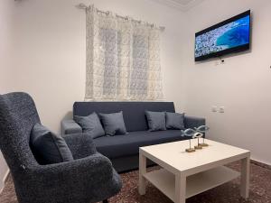 a living room with a blue couch and a table at Marina Helios Home in Áyios Yeóryios