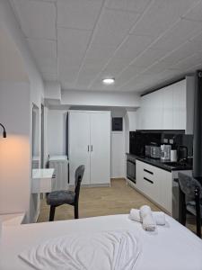 Una habitación blanca con una cama y una cocina. en Saranda Apartments Izabela, en Sarandë