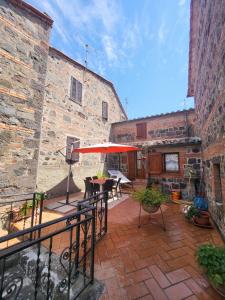 an outdoor patio with an umbrella and tables and chairs at La Casa Del Viandante in Radicofani