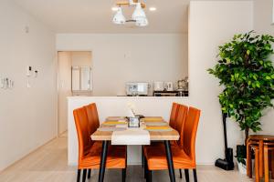 a dining room with a table and orange chairs at solf 世冨慶 in Nago