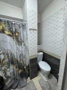 Un baño con inodoro y cortina de ducha. en Квартира, en Karakol