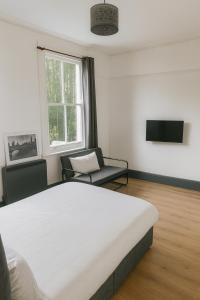 ロンドンにあるBethnal Green Nestの大きなベッドと椅子のある寝室