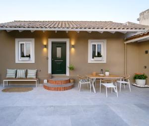 a patio with a green door and a table and chairs at La casa di Antonio Corfu in Alepou