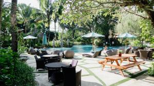 a patio with tables and chairs next to a pool at Esco Luxe Jimbaran in Jimbaran