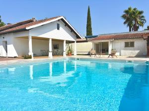a large blue swimming pool in front of a house at Villa luxueuse avec piscine chauffée in Gujan-Mestras