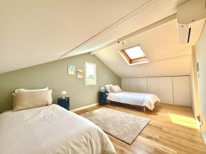 a attic bedroom with two beds and a window at Villa luxueuse avec piscine chauffée in Gujan-Mestras +20 photos