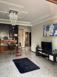a living room with a chandelier and a room with a table at Triana Guest House in Foz do Iguaçu