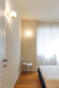 a bedroom with a bed and a chair next to a window at MilanLife Apartments - DTown Charme in Milan +20 photos