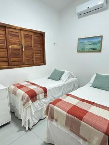 Dos camas en una habitación con paredes blancas. en Casa Aloha, en São Miguel do Gostoso