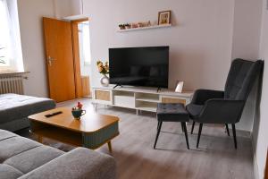 a living room with a flat screen tv and two chairs at Mahesars Home 2 in Ennepetal