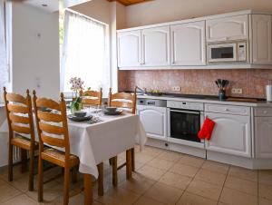 a kitchen with white cabinets and a table and chairs at Mahesars Home 2 in Ennepetal