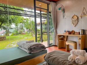 two beds in a room with a large window at Ki-ss House Coffee and Glamping in Di Linh