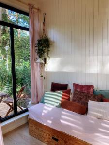 a bed in a room with a large window at Cozy Tiny House in the forest with spacious private garden in Zuidwolde