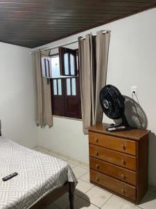 a bedroom with a bed and a dresser with a fan on it at kit-nets familiar in Belém