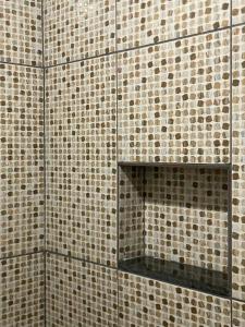 a bathroom with brown tiled walls and a mirror at kit-nets familiar in Belém