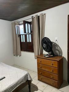 a bedroom with a bed and a dresser with a fan on it at kit-nets familiar in Belém