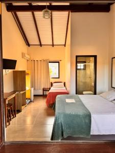 a hotel room with two beds and a desk at Pousada Village Garopaba in Garopaba