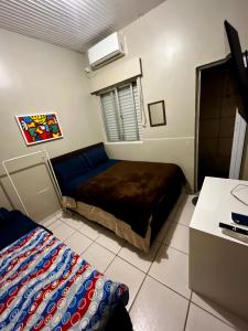 a small bedroom with a bed and a desk at Pousada DL in Pelotas
