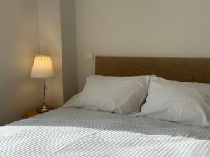 a bedroom with a bed with white sheets and a lamp at Apartamento Camino a Lancha in Miengo