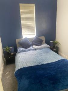 a bedroom with a bed with blue sheets and a window at Spacious Guest House Thornton Road, London in London