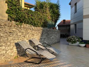 a pair of benches sitting next to a stone wall at Apartmento Camino a Lancha cerca de la Playa de Usgo y Robayera in Miengo