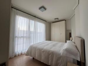 a bedroom with a white bed and a large window at Apartmento Camino a Lancha cerca de la Playa de Usgo y Robayera in Miengo