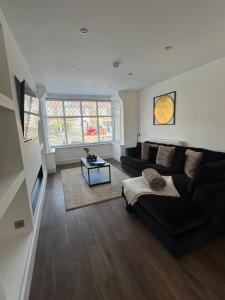 a living room with a black couch and a table at Rhos On Sea Getaway in Rhôs-on-Sea