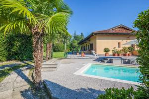 a palm tree in front of a house with a swimming pool at Residenz Vogino in Baveno