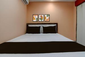a bedroom with a bed with two paintings on the wall at Hotel O Prasad Inn in Ballygunge