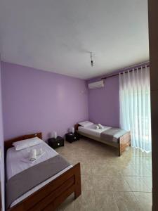 two beds in a room with purple walls at Dajanas apartment in Këlcyrë