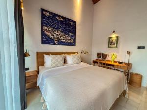 une chambre avec un grand lit blanc et un bureau dans l'établissement Uma Ugeng Cemagi 2 BR, à Cemagi 35 autres photos