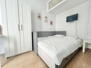 a white bedroom with a bed and a tv at Studio aux portes de Paris in Gentilly