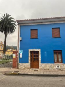 a blue building with a door and a palm tree at La Casa De La Arena in San Juan de la Arena