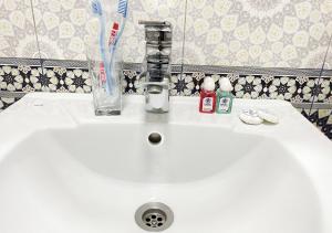un lavabo blanco con cepillos de dientes y cristal en Faxriddin East Hotel, en Bukhara