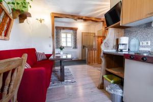 a kitchen and a living room with a red couch at Ferienwohnung am Abbrandtnergut 
