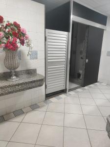 a bathroom with a vase of flowers on a tile floor at Nova Jerusalém in Cianorte