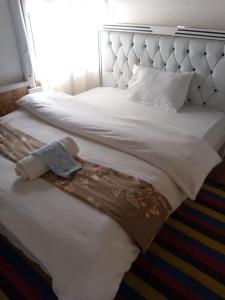 a white bed with a blanket and a teddy bear on it at Elmadel Coffee Gardens 4Bed Rustic Wooden House in Machakos