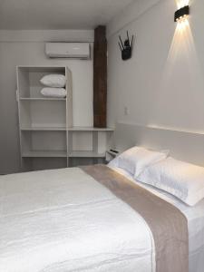 una camera da letto con un letto con lenzuola e asciugamani bianchi di Casa Torta 01 a Gramado