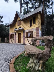 una piccola casa gialla con una panchina davanti di Casa Torta 01 a Gramado