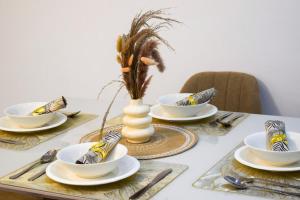 a table with plates and bowls and a vase on it at Appartement Grenoble in Yaoundé
