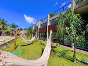 a resort with hammocks in front of a building at Apartamento Luxo em Japaratinga in Japaratinga