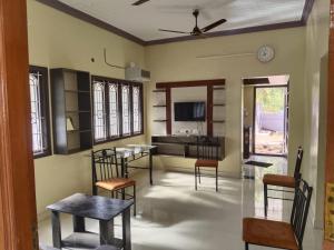 a living room with a table and chairs and a bed at Grace Homestay in Tiruchchendūr