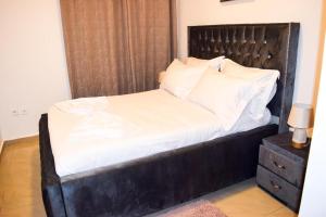 a bed with a black headboard and white sheets at Appartement Genève in Yaoundé