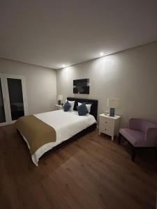 a bedroom with a large bed and a pink chair at The Place to Stay ! in Póvoa de Santa Iria