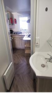 a white bathroom with a sink and a kitchen at WOW Holidays - 8 Person, 5 Star Mobile-Home with Terrace in Gastes