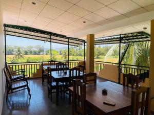 a dining room with tables and chairs and a balcony at Yala Hotel Grand View in Tissamaharama