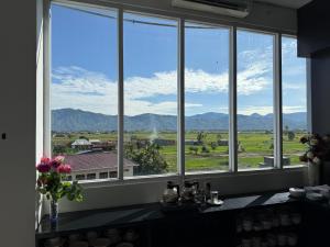 a large window with a view of a field and mountains at Hotel Grand Kerinci Sungai Penuh - Syariah in Sungaipenuh