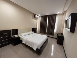 a bedroom with a bed and a flat screen tv at Hotel Grand Kerinci Sungai Penuh - Syariah in Sungaipenuh
