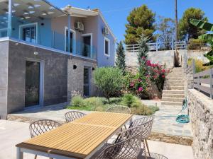 une table et des chaises en bois devant une maison dans l'établissement Villa Aurora amazing seaview to Lefkada - Meganisi, à Plagiá
